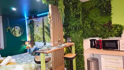 a room with a green wall with a table and stools at Cap Jungle Evasion: Cinema Netflix King size in Limoux