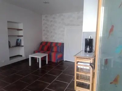 a living room with a red couch and a table at Studio équipé 2 personnes, Port la Nouvelle centre in Port-la-Nouvelle
