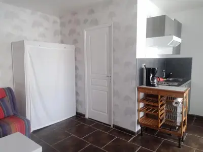 a small kitchen with a white door and a table at Studio équipé 2 personnes, Port la Nouvelle centre in Port-la-Nouvelle