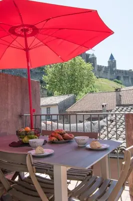 a table with plates of food and a red umbrella at Le Saint Gimer - Vue sur la Cité Médiévale - Climatisation in Carcassonne