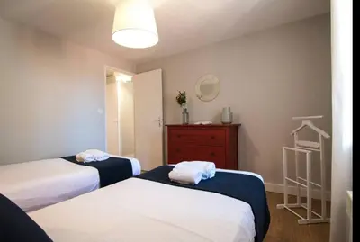 a bedroom with two beds and a dresser and a mirror at Le Saint Gimer - Vue sur la Cité Médiévale - Climatisation in Carcassonne