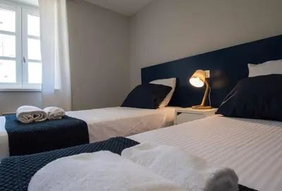 a bedroom with two beds and a lamp and a window at Le Saint Gimer - Vue sur la Cité Médiévale - Climatisation in Carcassonne