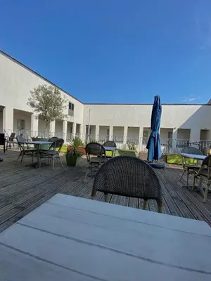 a deck with tables and chairs and an umbrella at Douce France in Cuxac-dʼAude
