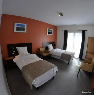 a hotel room with two beds and a chair at Douce France in Cuxac-dʼAude