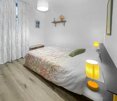 a white bedroom with a bed with a yellow lamp at Le Petit Paradis de Carcassonne in Carcassonne