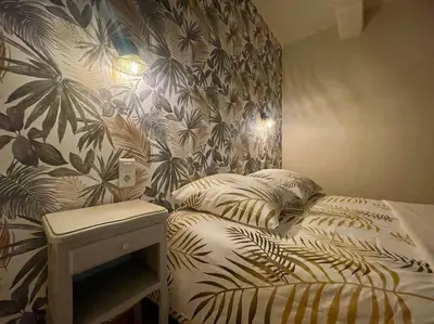 a bedroom with a bed with a tropical wallpaper at La Traverse - au pied de la Cité Médiévale - Clim et terrasse in Carcassonne
