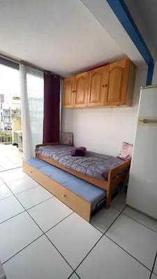 a bedroom with a bed with wooden cabinets and a refrigerator at La terrasse de Gruissan in Gruissan