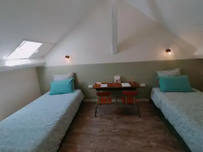 two beds in a room with a table and two chairs at L'école buissonnière in Laroque-dʼOlmes