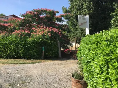 a sign in front of some bushes with pink flowers at La Barthe Haute in Puycalvel Lautrec
