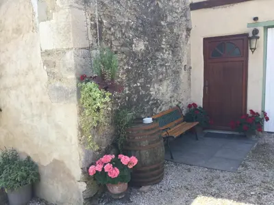 a wooden bench next to a building with flowers at La Barthe Haute in Puycalvel Lautrec