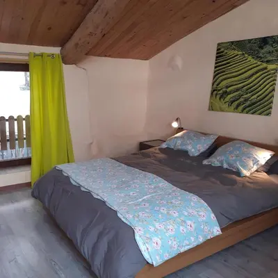 a bedroom with a bed with a green curtain at Les deux arches in Caunes-Minervois