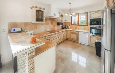 a large kitchen with white appliances and wooden cabinets at Pet Friendly Home In Pouzols-Minervois in Pouzols-Minervois