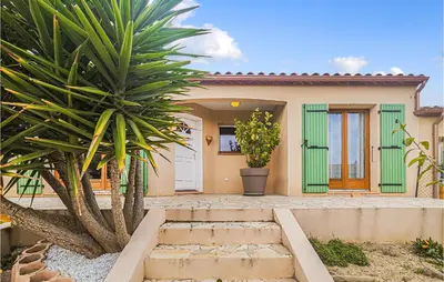 a house with a palm tree in front of it at Pet Friendly Home In Pouzols-Minervois in Pouzols-Minervois