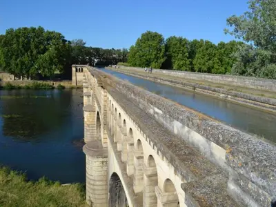 a bridge over a river next to a body of water at Tranquil Villa, Nature s Embrace in Cazouls-lès-Béziers