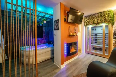 a room with a bathroom with a tub and a tv at Le Lovely Gruissanais - Balneo & Sauna in Gruissan