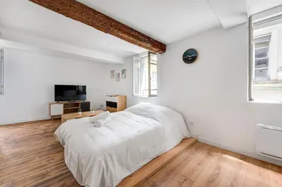 a white bedroom with a bed and a tv at Les studios Jean Bringer - Carcassonne centre-ville in Carcassonne