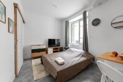 a bedroom with a bed and a desk and a window at Les studios Jean Bringer - Carcassonne centre-ville in Carcassonne