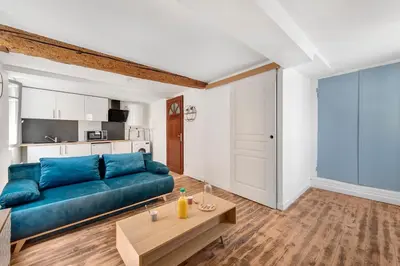 a living room with a blue couch and a table at Les studios Jean Bringer - Carcassonne centre-ville in Carcassonne