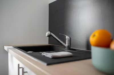 a kitchen sink with a faucet and an orange on a counter at Les studios Jean Bringer - Carcassonne centre-ville in Carcassonne