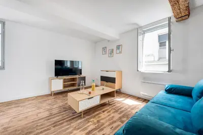 a living room with a blue couch and a table at Les studios Jean Bringer - Carcassonne centre-ville in Carcassonne