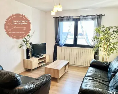a living room with a couch and a tv at Le bassin - Vue canal du midi avec climatisation et garage in Castelnaudary