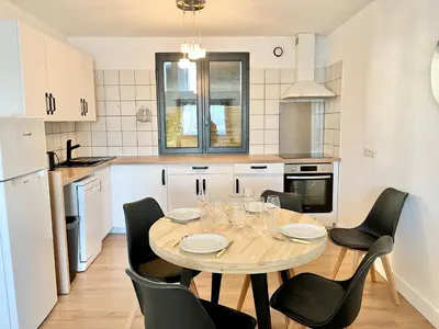 a kitchen with a table and chairs in a kitchen at Le bassin - Vue canal du midi avec climatisation et garage in Castelnaudary
