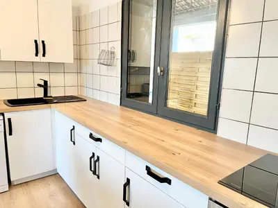 a kitchen with white cabinets and a wooden counter top at Le bassin - Vue canal du midi avec climatisation et garage in Castelnaudary