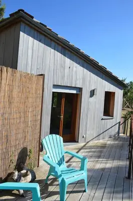 a blue rocking chair on a deck with a building at Chalet, quiet, with view and pool (at summertime) in Ventenac-Cabardès