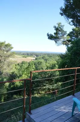 a wooden deck with a bench and a view of trees at Chalet, quiet, with view and pool (at summertime) in Ventenac-Cabardès