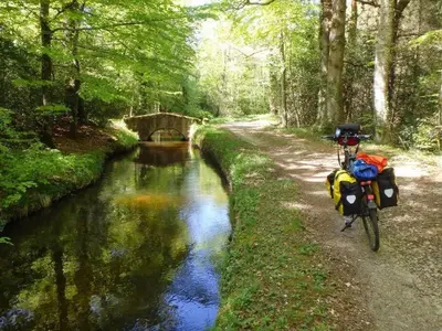a bike parked on a path next to a river at Chalet, quiet, with view and pool (at summertime) in Ventenac-Cabardès