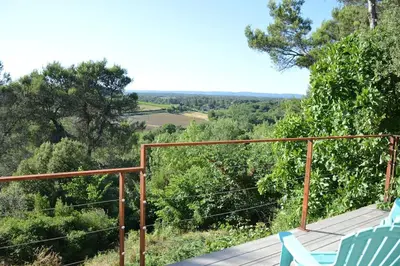 a deck with two chairs and a view of trees at Chalet, calme, absolu, superbe vue, et piscine (en été) in Ventenac-Cabardès