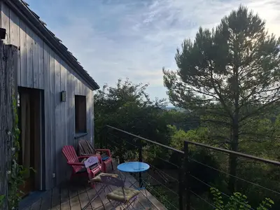 a balcony with two chairs and a table and a tree at Chalet, calme, absolu, superbe vue, et piscine (en été) in Ventenac-Cabardès