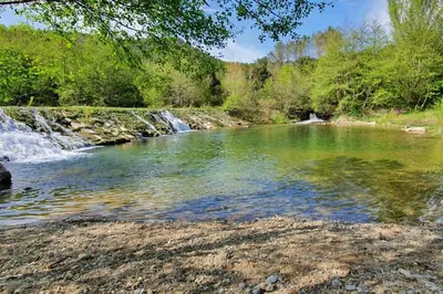 a river with a waterfall in the background at Maison chaleureuse près de lagrasse corbières in Saint-Pierre-des-Champs