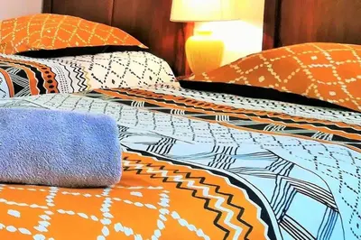 a bed with orange and blue comforter and pillows at Maison chaleureuse près de lagrasse corbières in Saint-Pierre-des-Champs