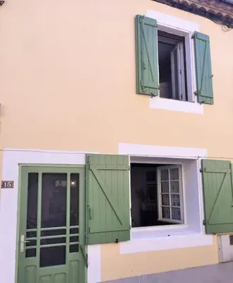 a building with green doors and a window at Maison chaleureuse près de lagrasse corbières in Saint-Pierre-des-Champs
