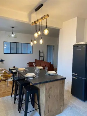 a kitchen with a table with chairs and a refrigerator at Chez Julie in Castres