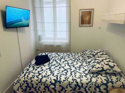 a bed in a room with a television on the wall at Le P'tit Stud' in Castres