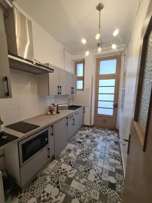 a kitchen with white cabinets and a tile floor at Spacious Luxury 2 bed appartment in Carcassonne