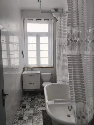a white bathroom with a tub and a toilet and a window at Spacious Luxury 2 bed appartment in Carcassonne