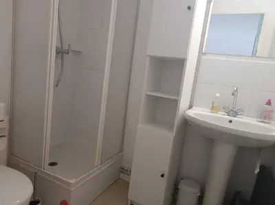 a white bathroom with a shower and a sink at Pavillon 5 personnes in Port-la-Nouvelle