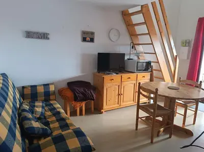 a living room with a couch and a table and a chair at Pavillon 5 personnes in Port-la-Nouvelle