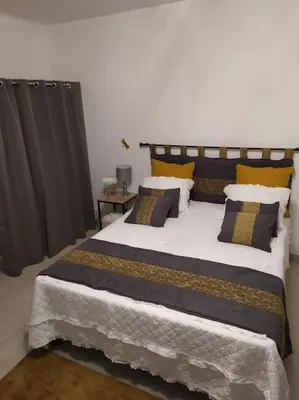 a bedroom with a large bed with yellow and blue pillows at Studio proche du centre-ville in Carcassonne