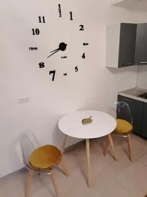 a white table and two chairs and a clock on a wall at Studio proche du centre-ville in Carcassonne