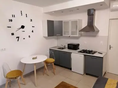 a kitchen with a table and a stove and a clock on the wall at Studio proche du centre-ville in Carcassonne