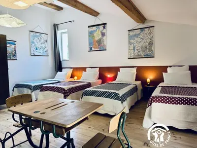 a room with four beds and a wooden table at Gîte de caractère La Grange Saint Papoul in Saint-Papoul