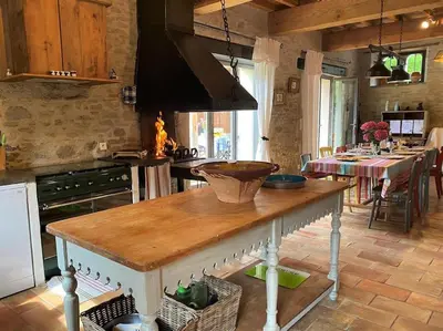 a kitchen with a table in a kitchen with a stove at Gîte de caractère La Grange Saint Papoul in Saint-Papoul