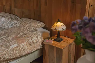 a lamp on a wooden table next to a bed at Fount Estremiero - Chambres & tables d'hôtes in Castans