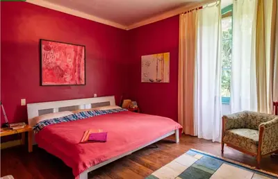 a red bedroom with a bed and a chair at DEMEURE BERGAMOTE de FONTIERS in Fontiers-Cabardès