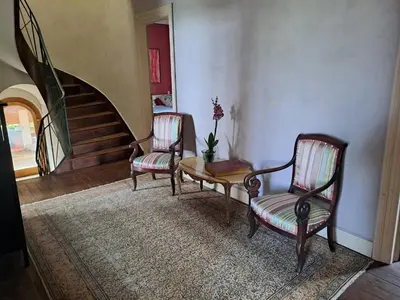 a living room with two chairs and a table and a staircase at DEMEURE BERGAMOTE de FONTIERS in Fontiers-Cabardès