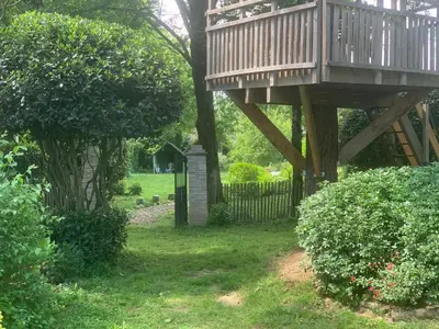 a tree house with a deck in a yard at Sous le Tilleul de la Condomine in Payrin-Augmontel